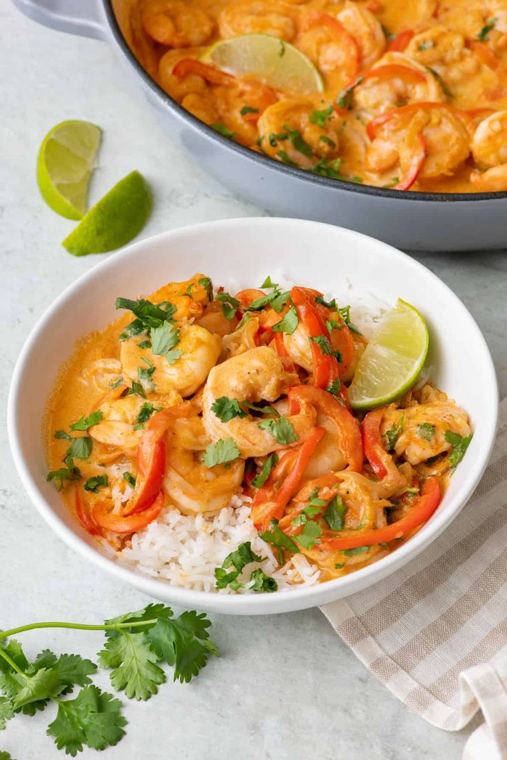 a white bowl filled with shrimp, rice and cilantro on top of a table