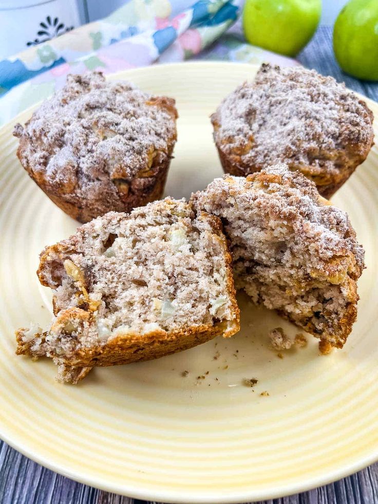 some muffins are on a plate with apples in the backgroung