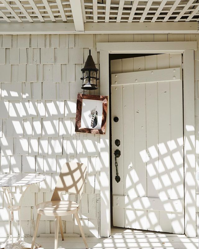 a chair and table sitting in front of a white door with a lantern on it