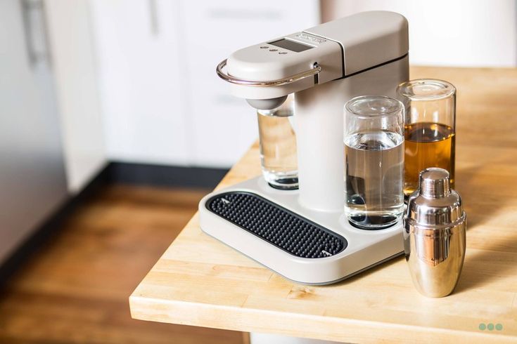 an espresso machine sitting on top of a wooden table next to two shot glasses