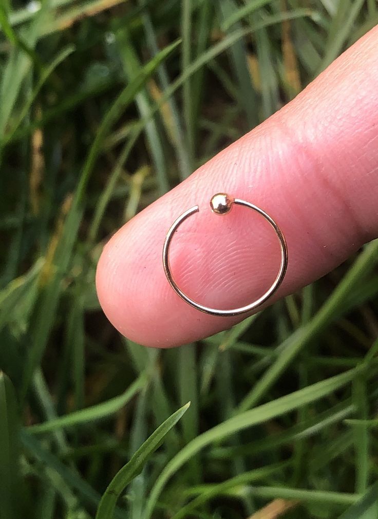 a person's finger with a ring on it in front of some green grass