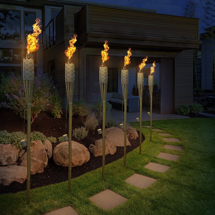 four torches lit up in front of a house