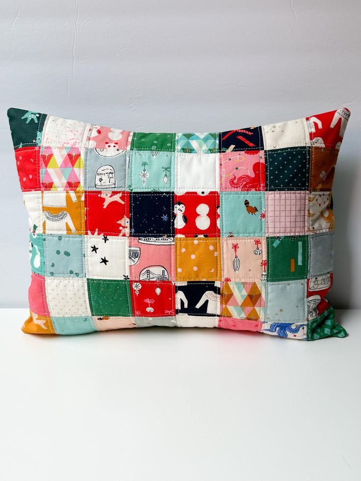 a colorful patchwork pillow sitting on top of a white table next to a wall