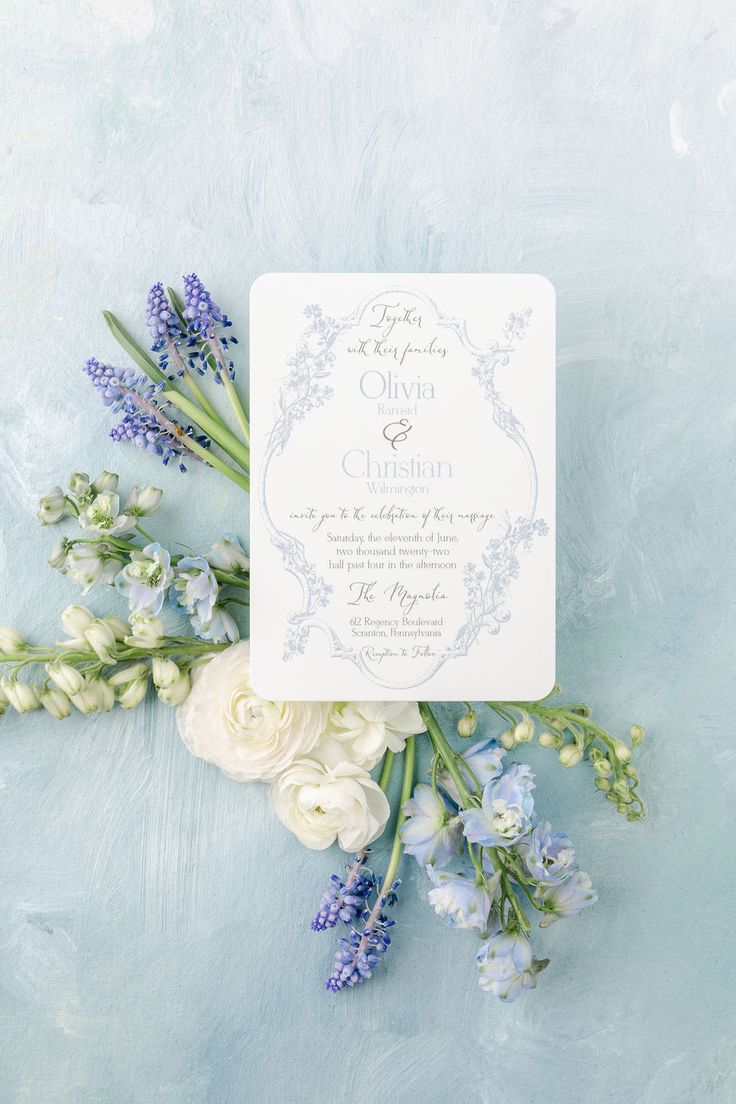 a wedding card and flowers on a blue background