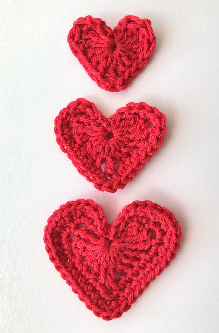 two crocheted hearts sitting next to each other on top of a white surface