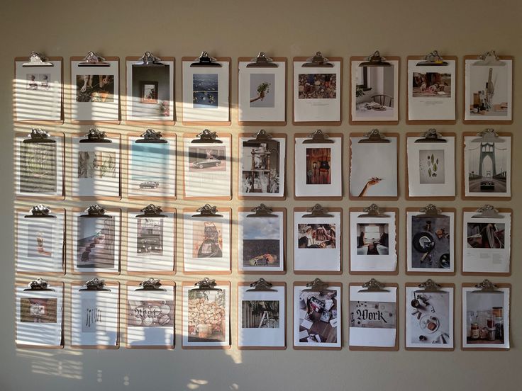 Wall with a 9 by 4 grid of clipboards with pages of a photo magazine clipped to each one Clipboard Photo Wall, Clipboard Gallery Wall, Clip Board Wall, Wall Magazine Ideas School, Boardroom Ideas, Retro Family Photos, Clipboard Wall Art, Clipboard Frames, Clipboard Wall