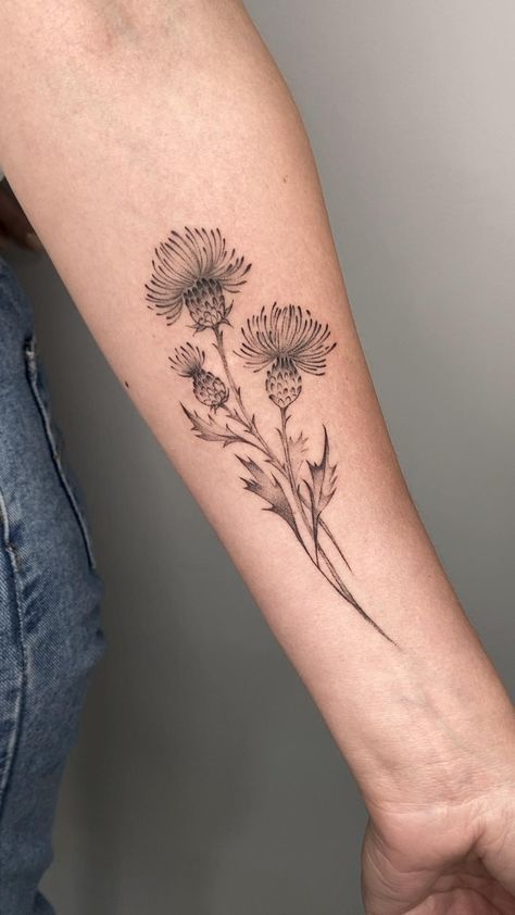 a woman's arm with flowers tattooed on the left side of her arm, in black ink