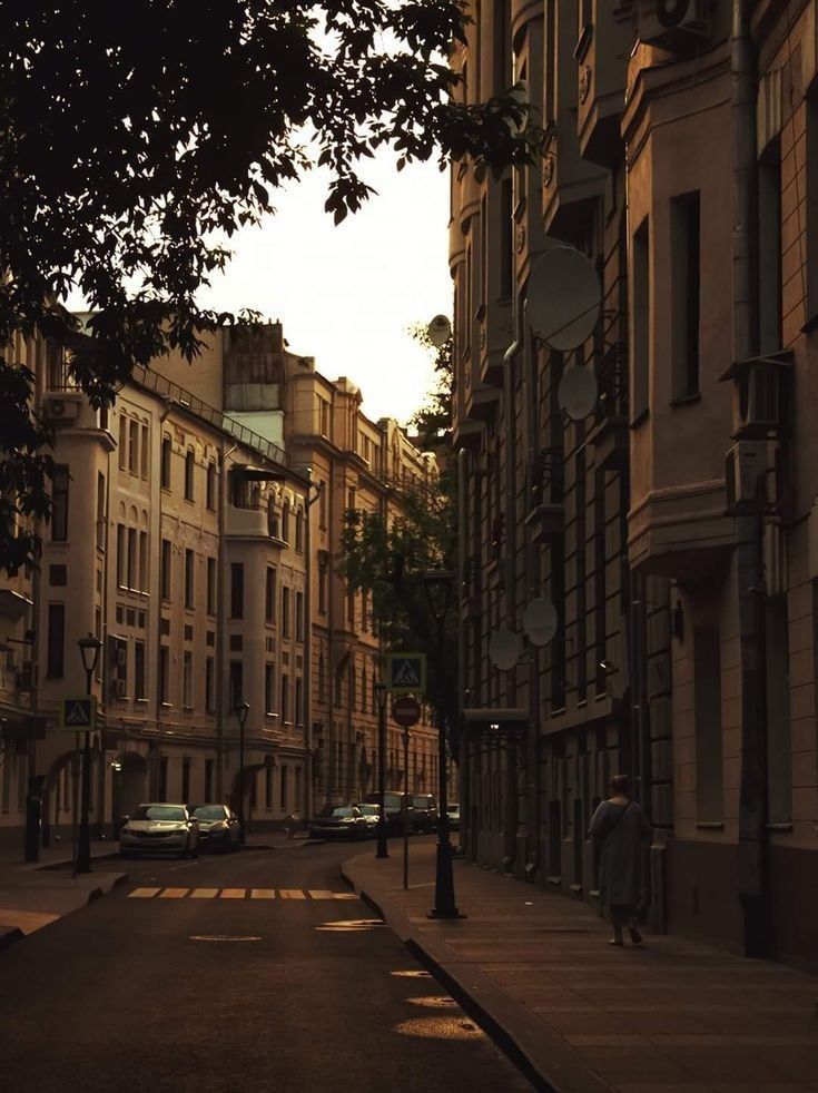 an empty city street with cars parked on both sides and tall buildings in the background