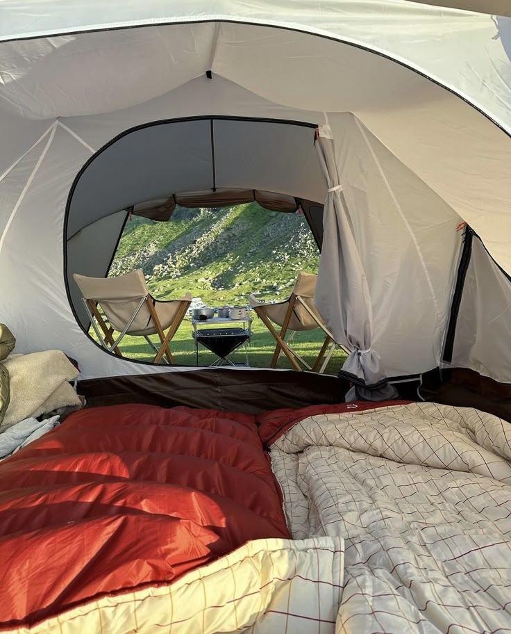 the inside of a tent with two chairs and a bed in it that is set up outside