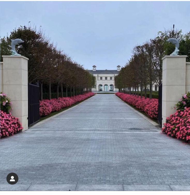 the entrance to a large mansion with pink flowers