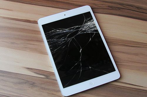 a broken tablet sitting on top of a wooden table