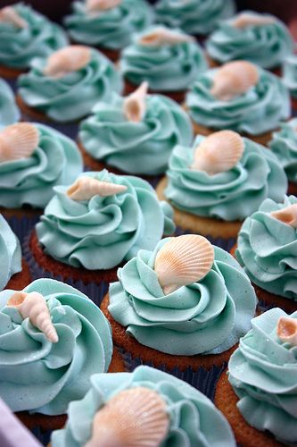 cupcakes with blue frosting and shells on them