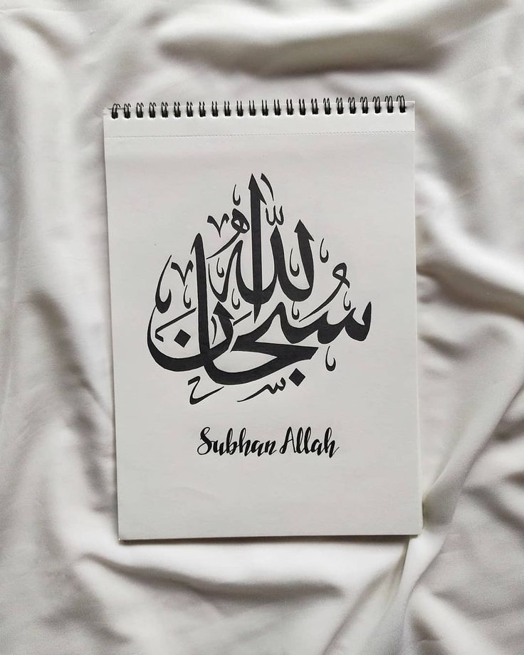 a spiral notebook with an arabic calligraphy written in black and white on a bed sheet