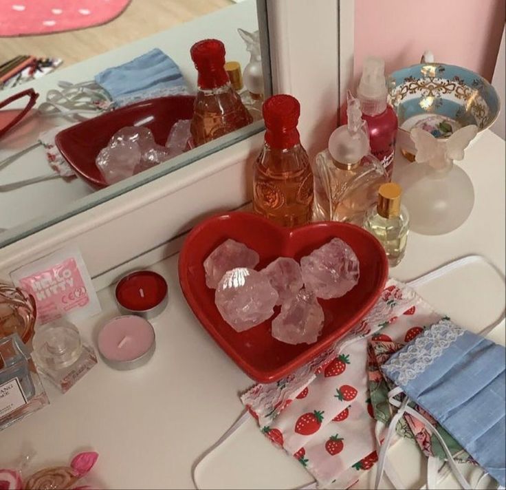 a heart shaped bowl sitting on top of a counter next to bottles and other items