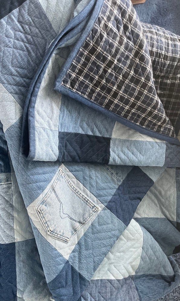 a blue and white quilt on top of a bed next to a pair of scissors