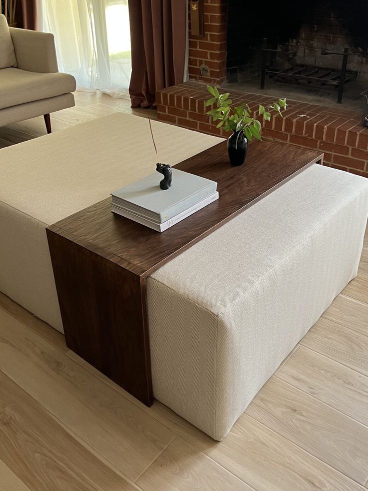 a coffee table with a book on it in front of a fireplace