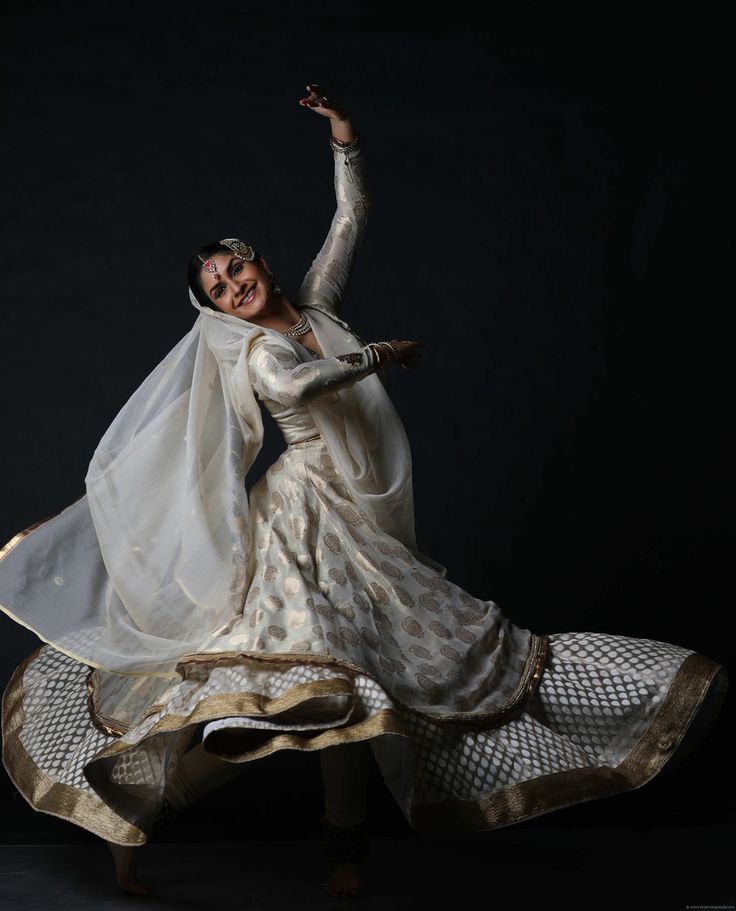 a woman in a white dress and veil is dancing with her arms spread out to the side