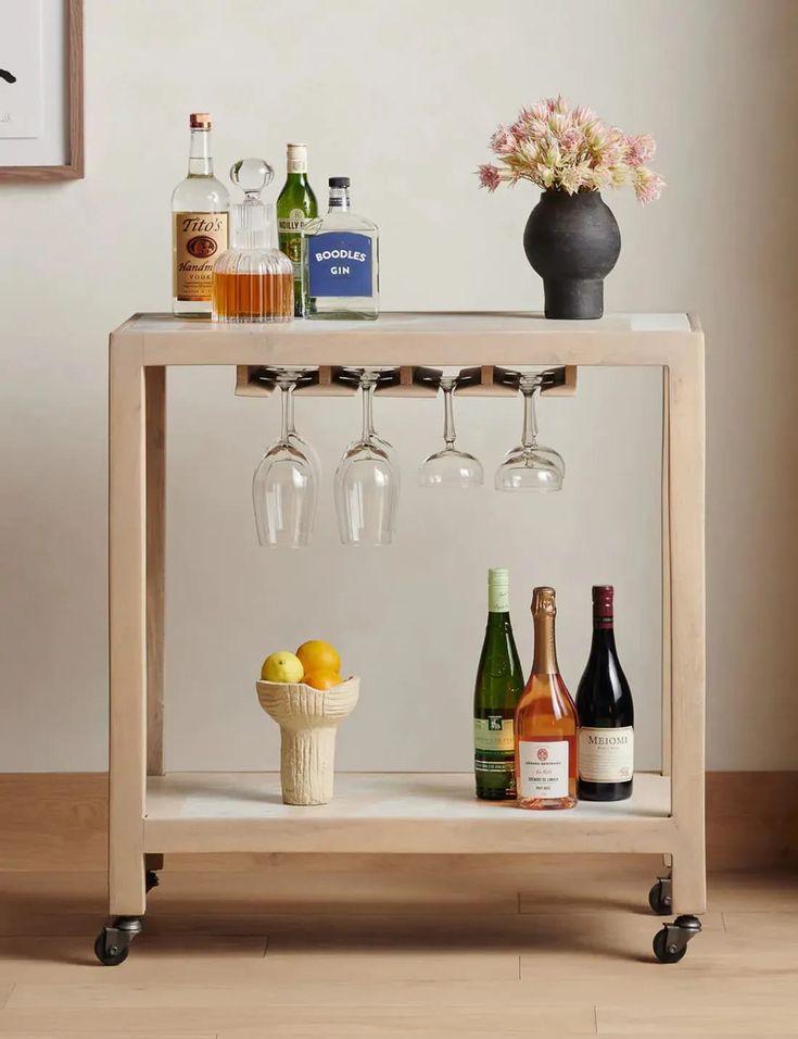 a wooden bar cart with wine glasses and bottles on it