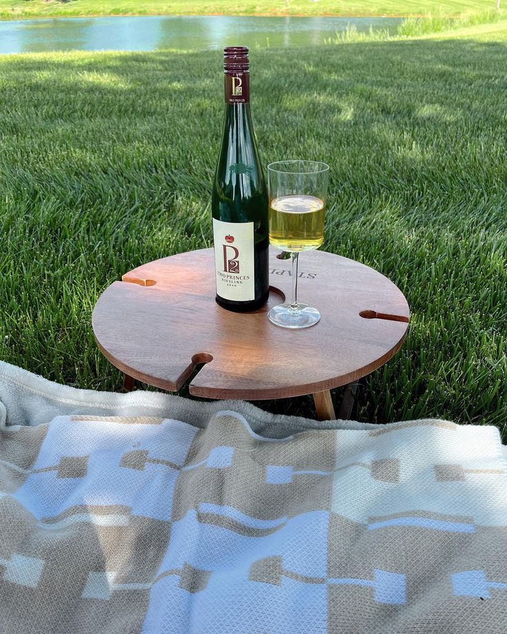 a bottle of wine sitting on top of a wooden table next to a glass of wine