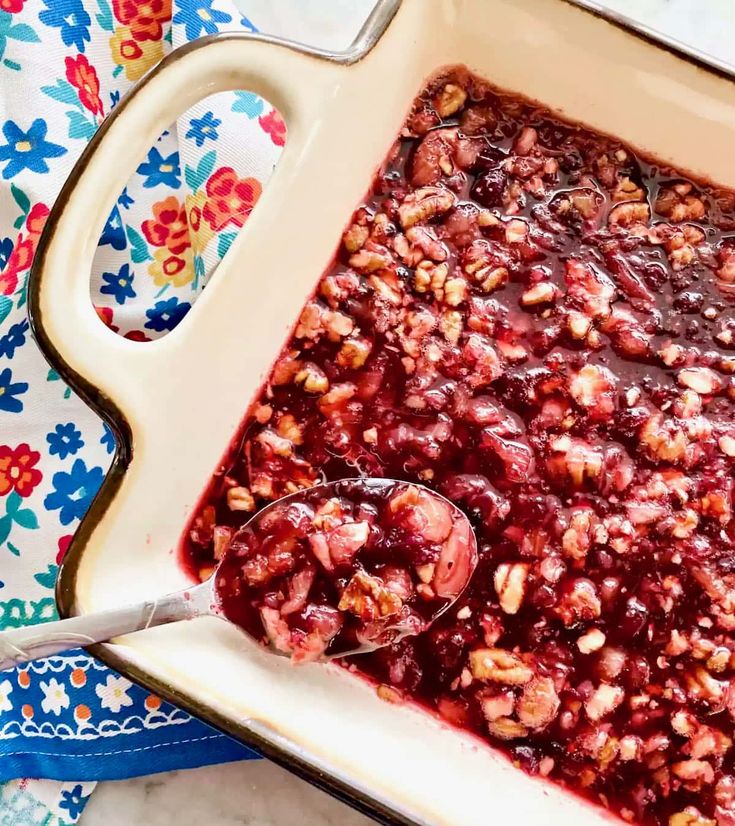 a close up of a dish of food on a table with spoons and flowers