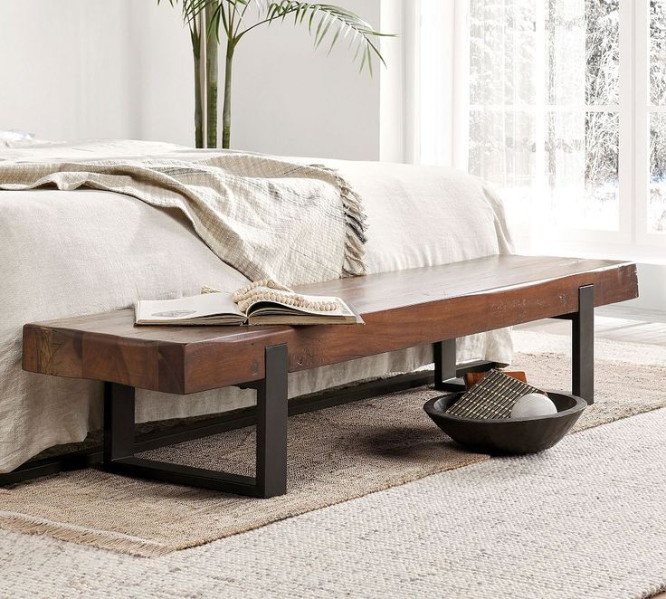 a wooden bench sitting on top of a rug next to a bed