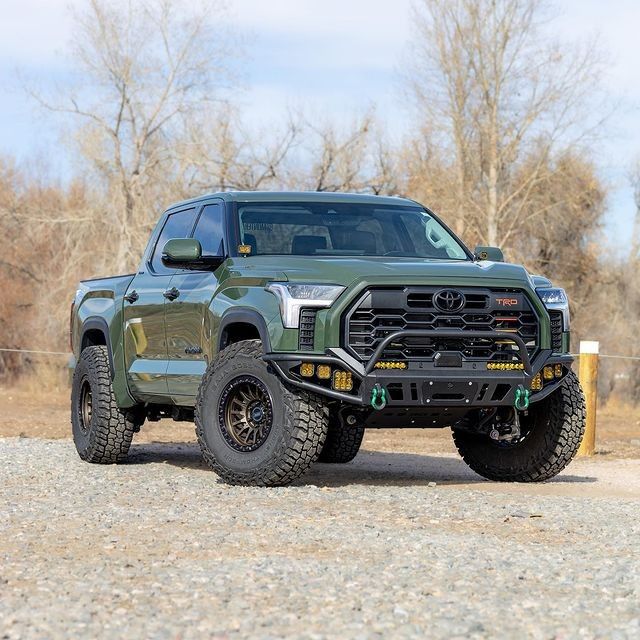 a green truck parked on top of a gravel road