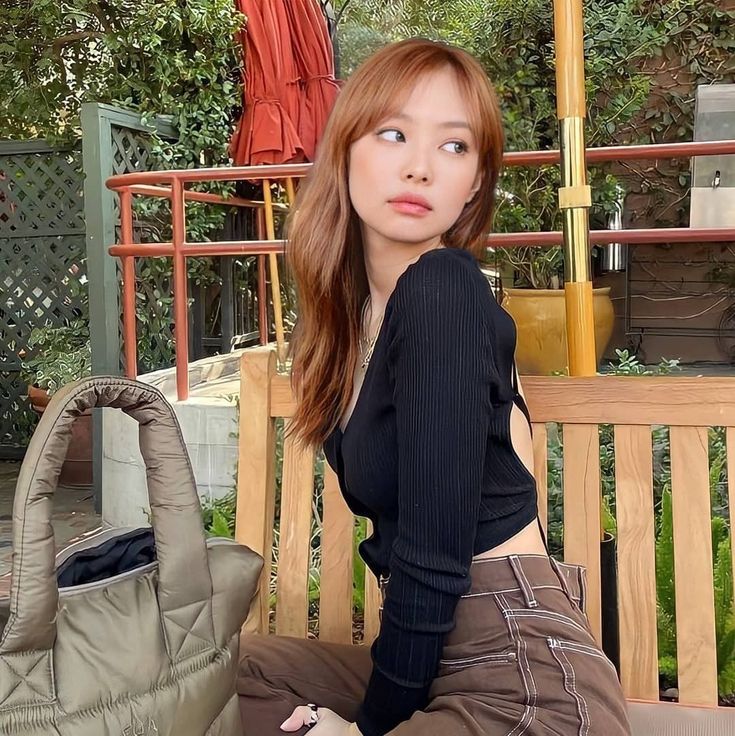 a woman sitting on a bench with an umbrella in the background and a purse behind her