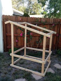 a wooden structure sitting in the middle of a yard with flowers growing out of it