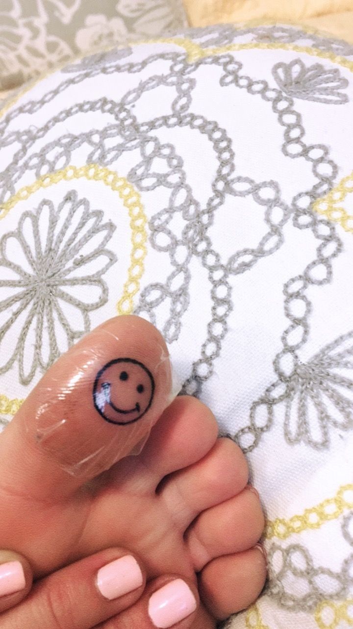 a person's foot with a smiley face drawn on the tip of their toe