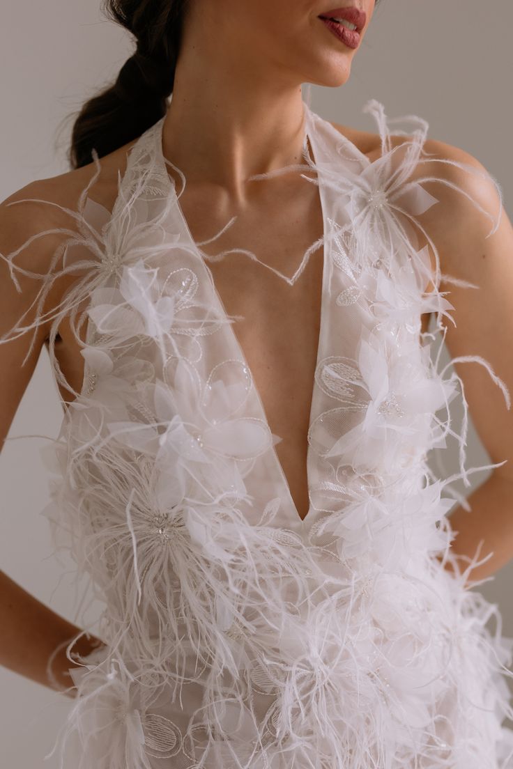 a woman wearing a white dress with feathers on it