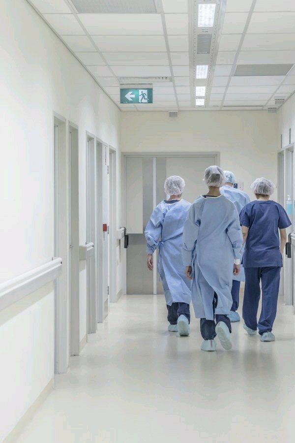 doctors walking down the hallway in scrubs and gowns to an operating room with doors open