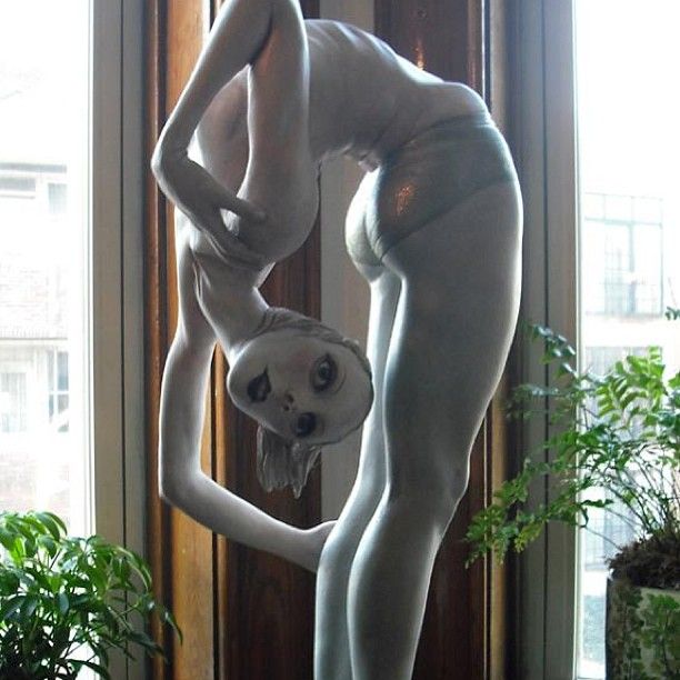 a statue of a woman with her hands on her hips in front of a window