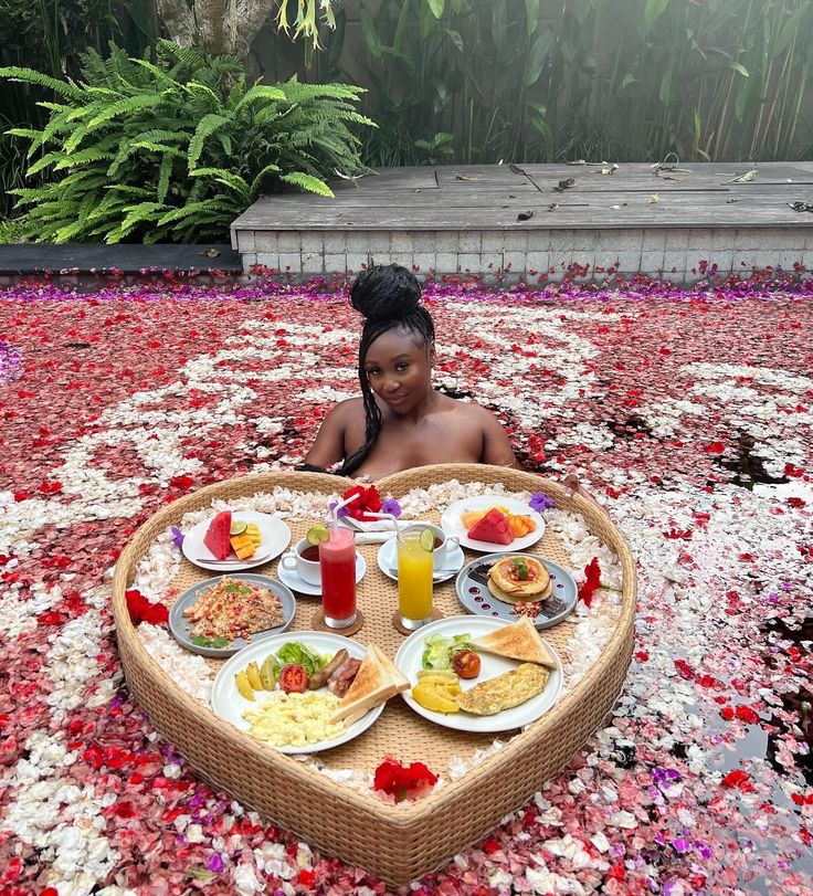 a woman sitting in the middle of a heart shaped table filled with food