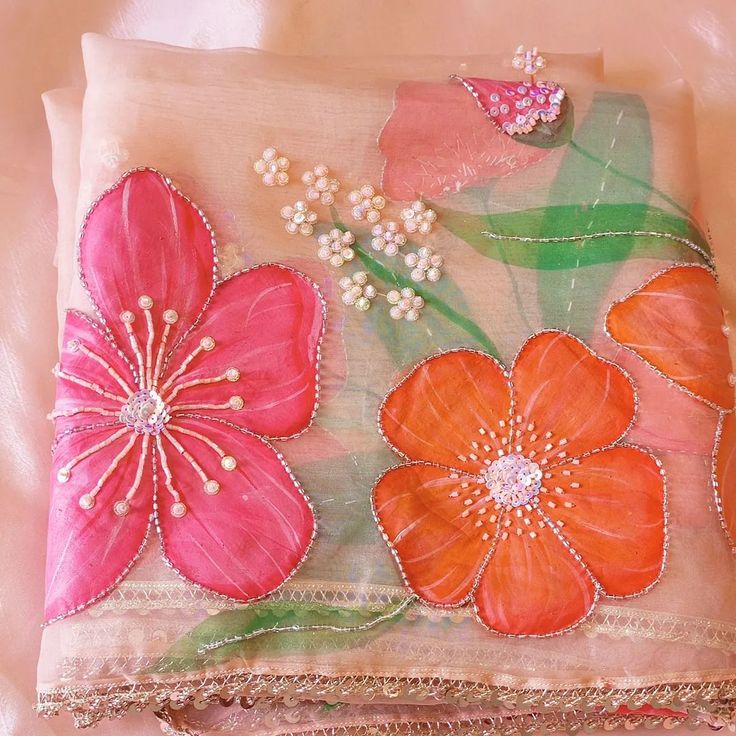 a pink and orange flowered design on a piece of cloth with beadings