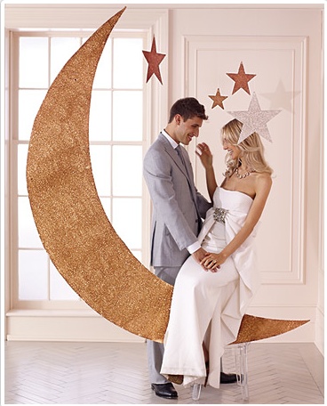 a man and woman standing next to each other in front of a large crescent moon