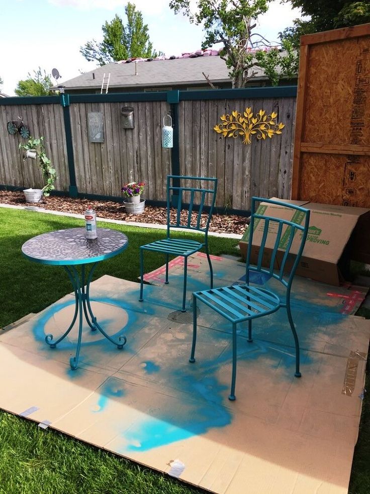 two chairs and a table sitting on top of a piece of cardboard in the grass