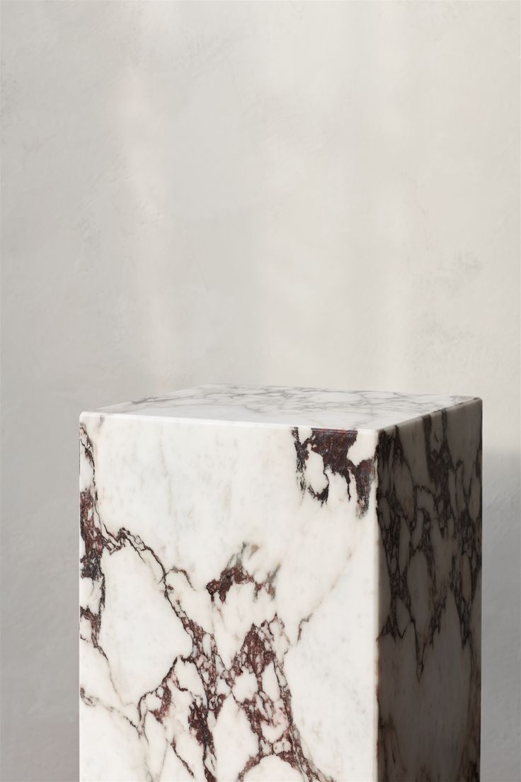 a white and brown marble block sitting on top of a wooden table next to a wall