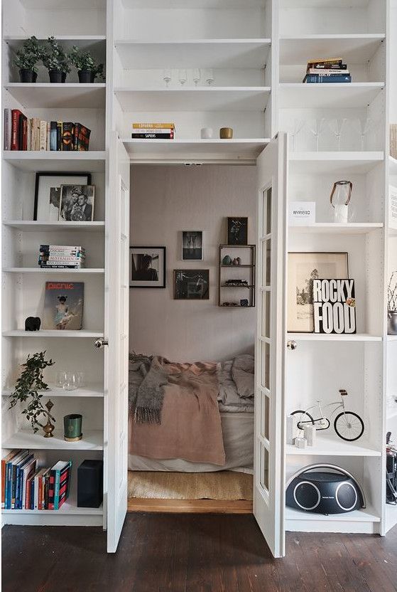 an open bookcase in the corner of a room filled with books and other items