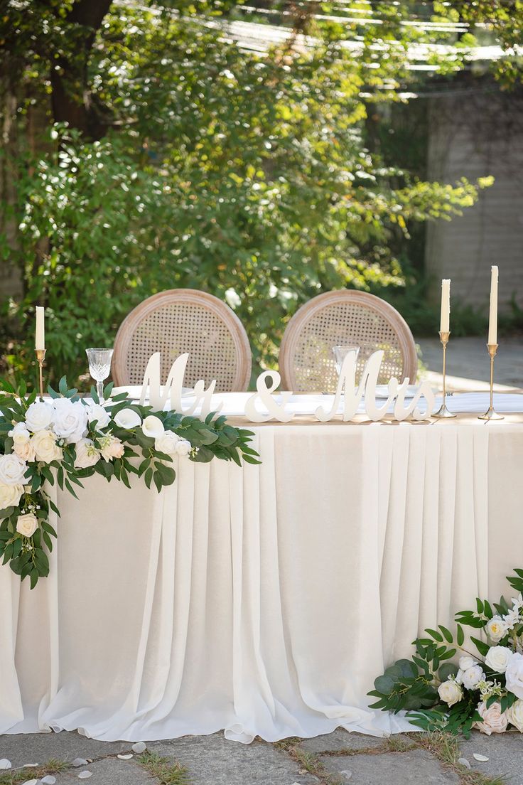 the table is set up with white flowers and greenery for an elegant wedding reception