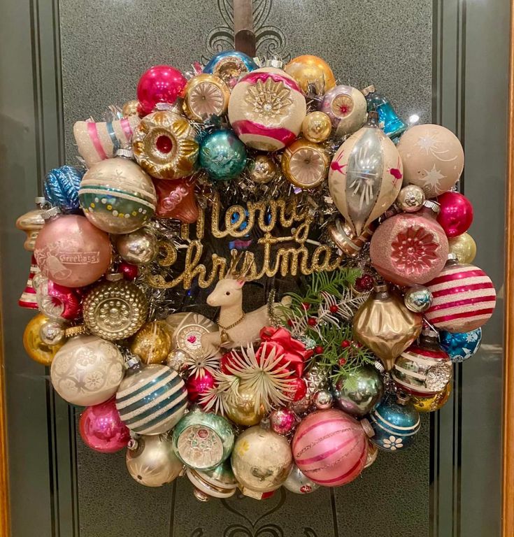 a christmas ornament wreath on a door decorated with ornaments and the words merry christmas