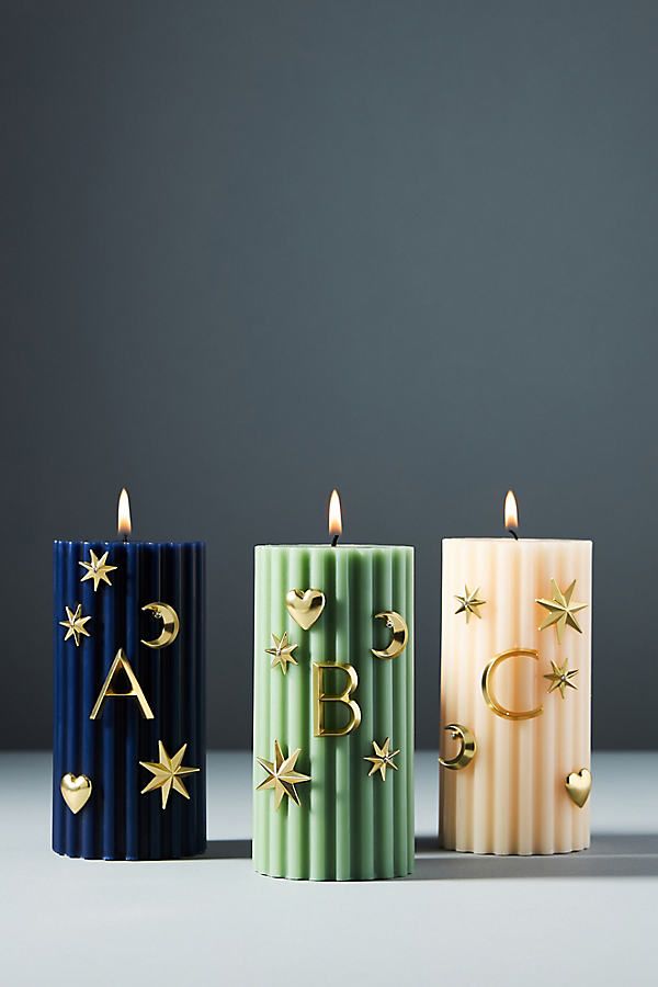 three candles with gold stars on them and one candle that has the letter b in it