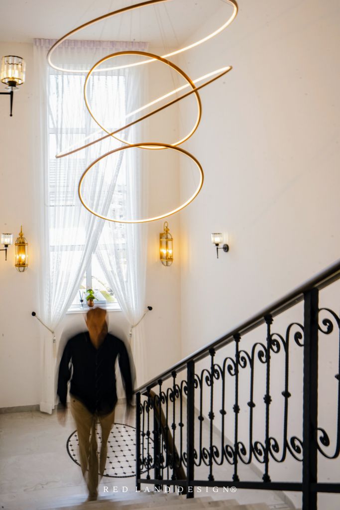 a man walking up the stairs in front of a large chandelier hanging from the ceiling