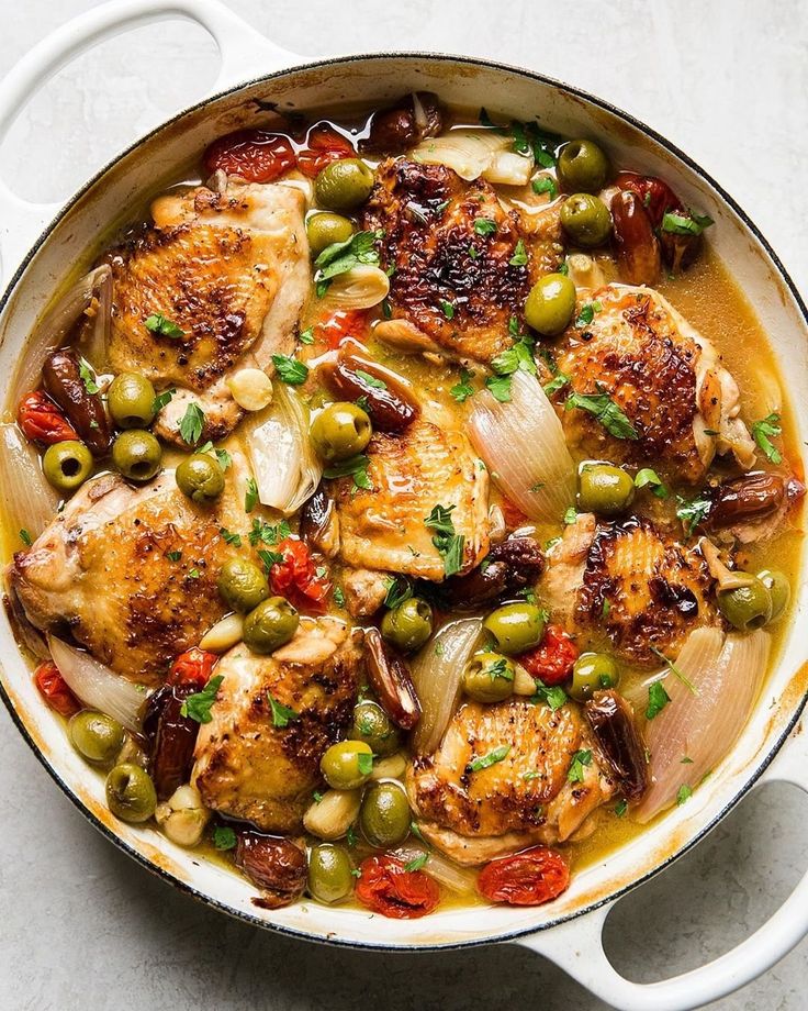 a pan filled with chicken, olives and onions