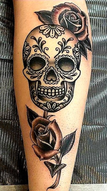 a woman's leg with a tattoo on it that has a skull and roses on it