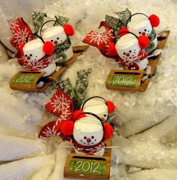 three snowmen are sitting on sleds in the snow with numbers written on them