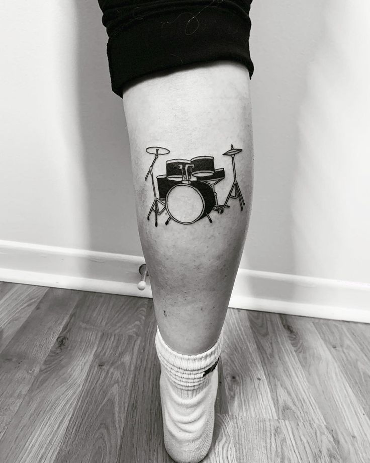 a person with a tattoo on their leg that has a drum and drums on it