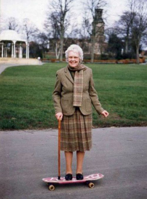 an older woman is standing on a skateboard