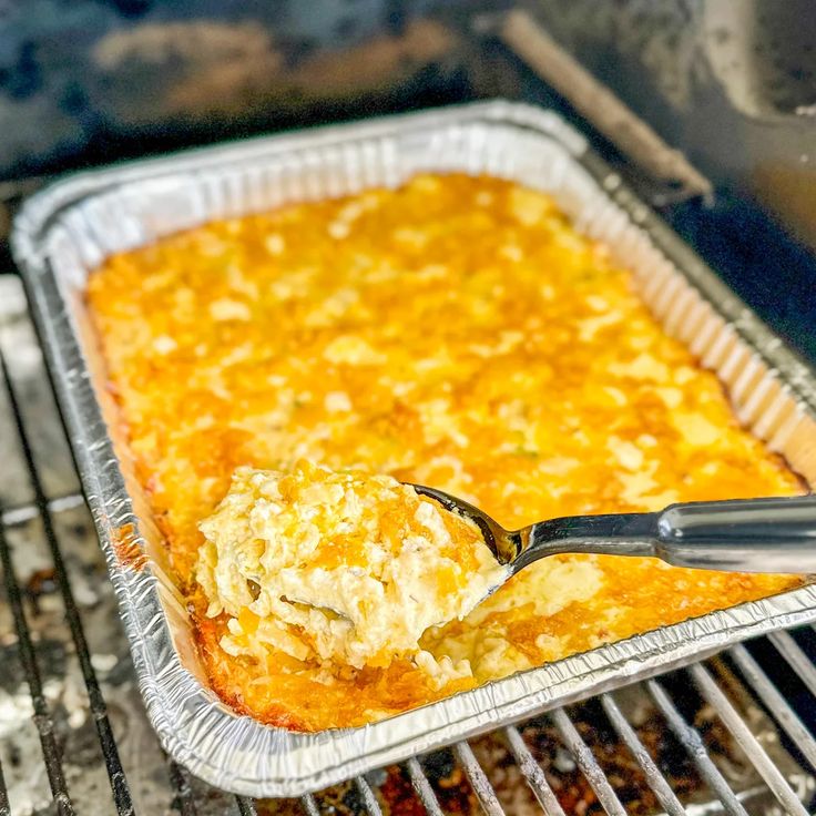 a casserole is being cooked in an oven with a spatula and tongs