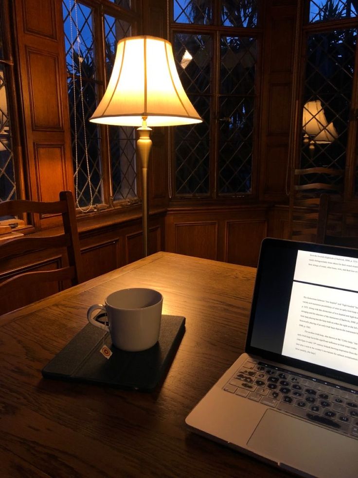 an open laptop computer sitting on top of a wooden table next to a coffee cup