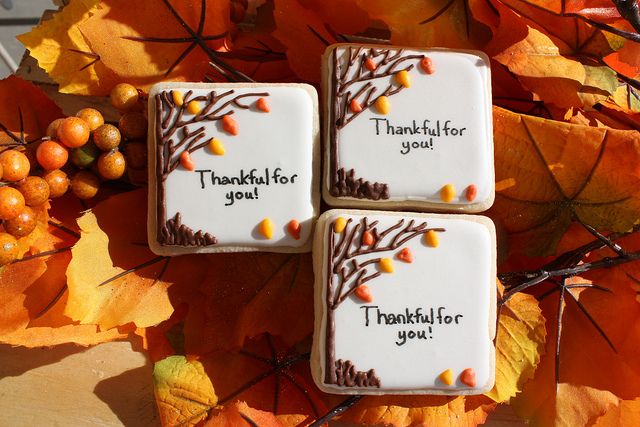 three decorated cookies sitting on top of a table next to autumn leaves and oranges